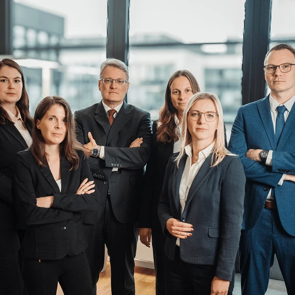 Schick gekleidetes Kanzleiteam vor moderner heller Fensterfront
