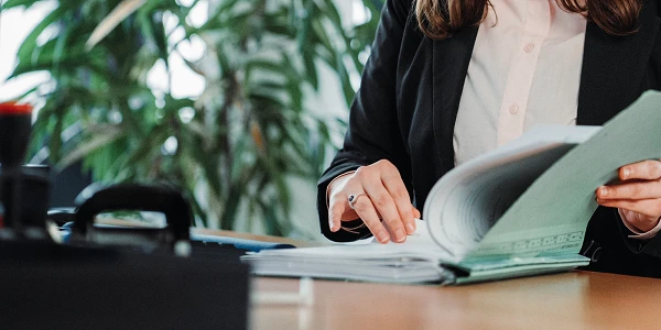 Nahaufnahme eines Ordners, in dem eine Frau in ihrem Büro blättert