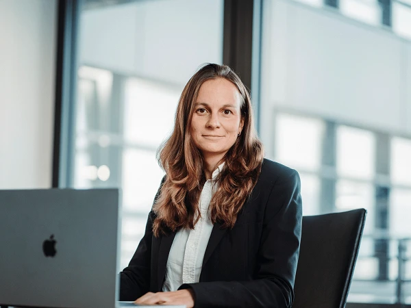 lächelnde Frau an Schreibtisch in modernem Büro mit Laptop